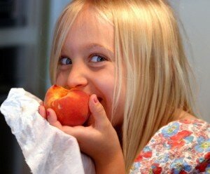 Girl eating a peach.